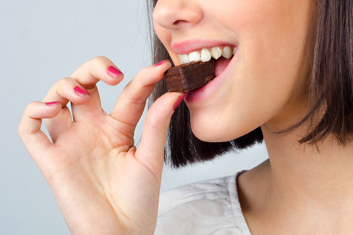 Woman eating chocolate with acne free skin