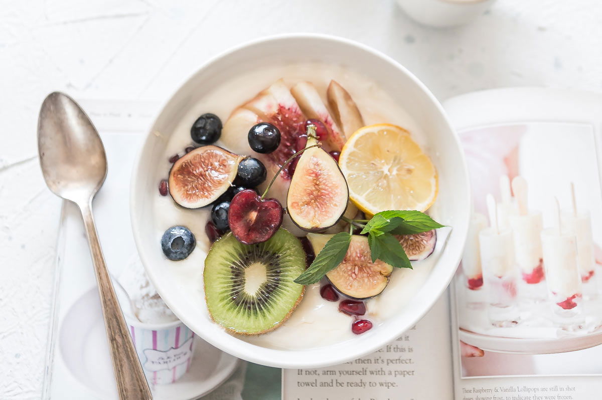 Bowl of yogurt with kiw fruit, lemon, figs, cherries, blueberries, melon and mint