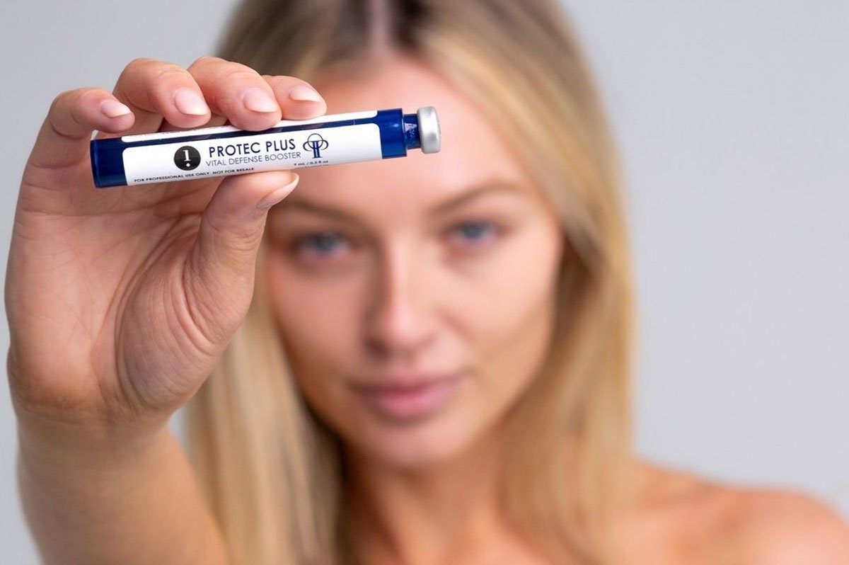 Young blonde woman holding a Protec Plus Hydrafacial Booster Serum
