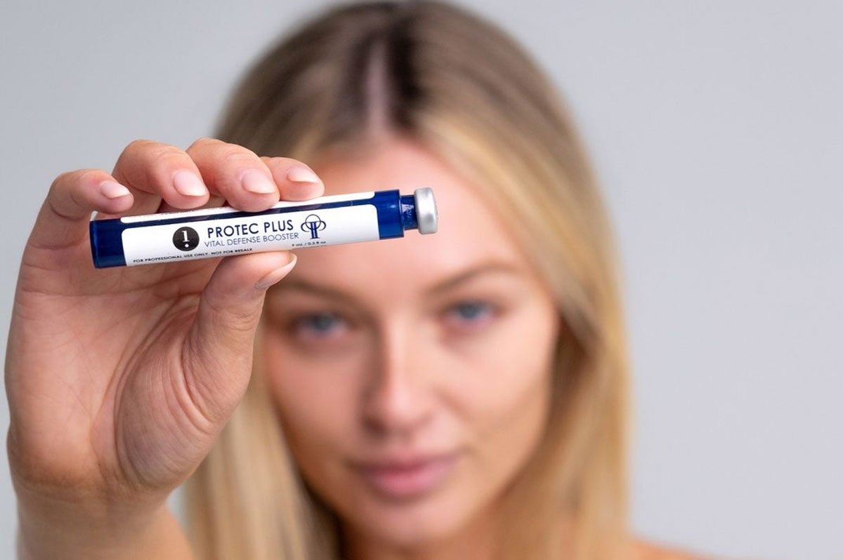 Young blonde woman holding a Protec Plus Hydrafacial Booster Serum