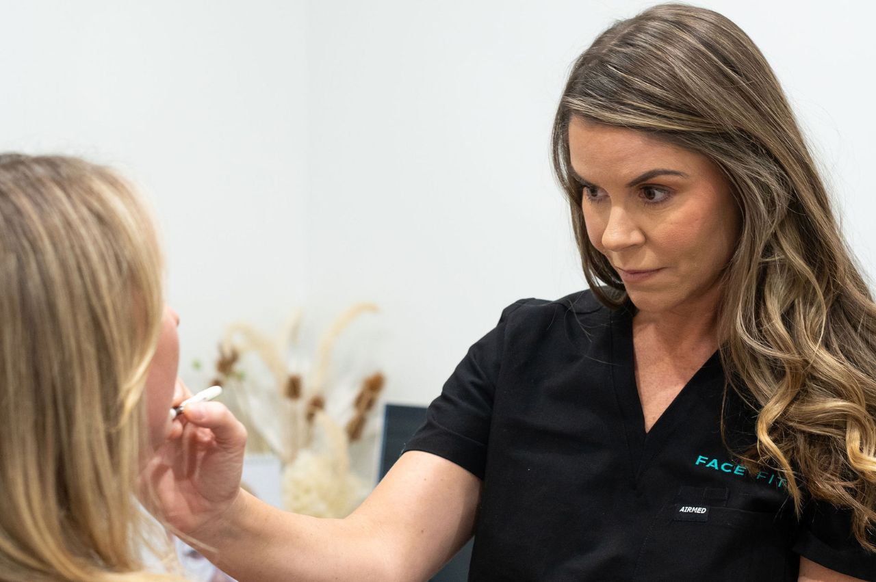 Cosmetic nurse assessing woman's skin health